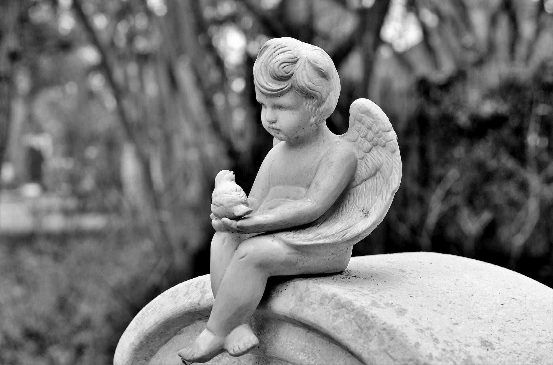 A statue of an angel sitting on top of a stone.