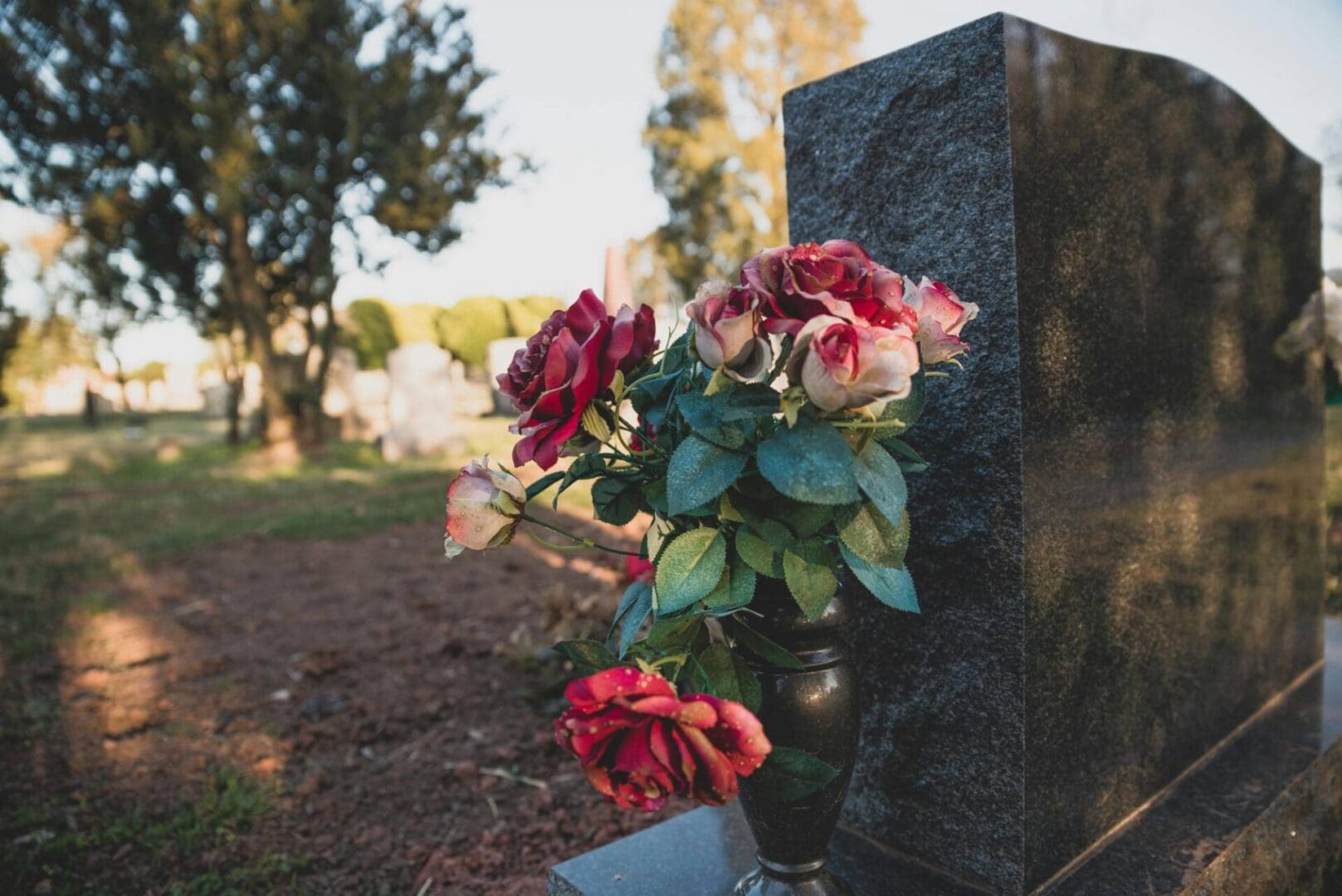 A vase of flowers on the side of a grave.