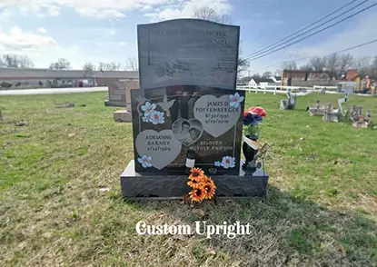 A grave with flowers on it in the middle of a field.