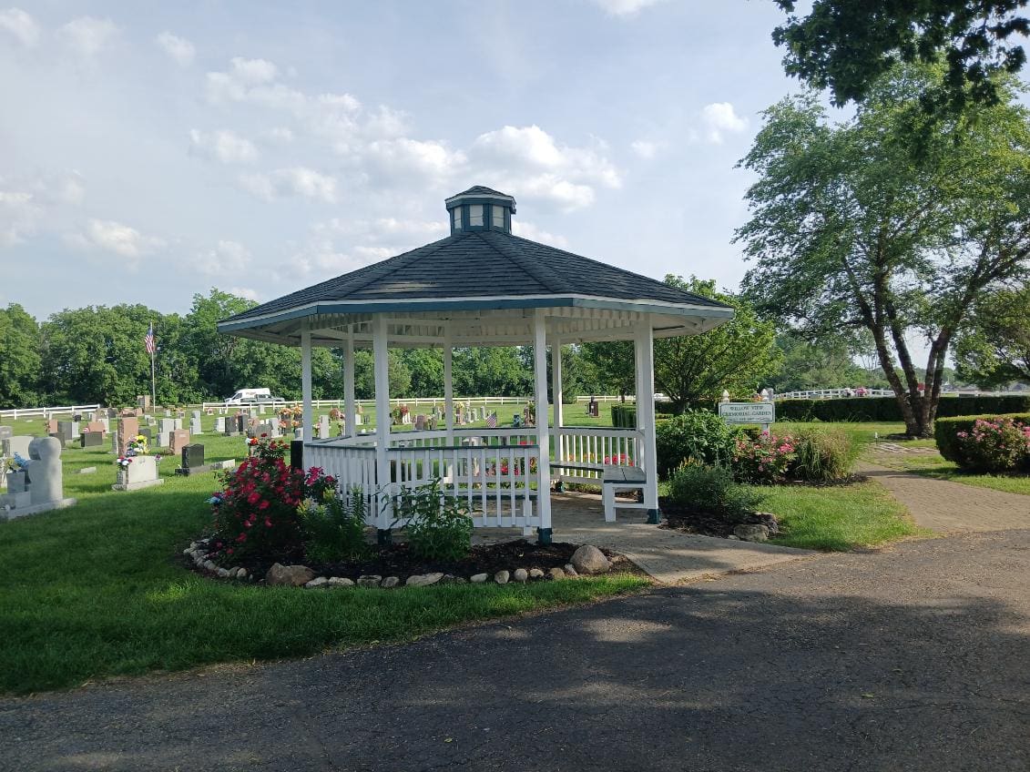 A white gazebo with flowers in the middle of it.