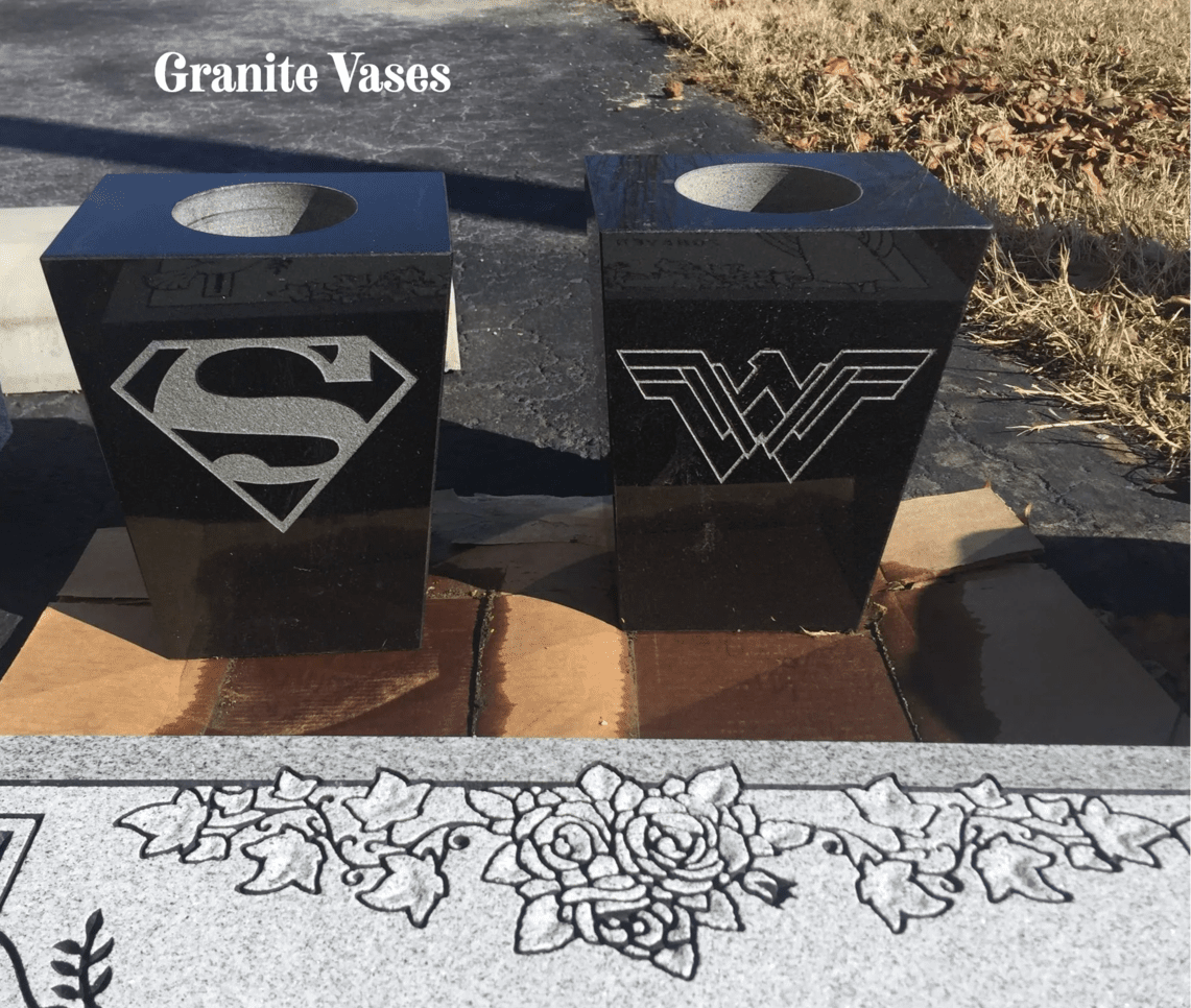 A couple of black granite vases sitting on top of a sidewalk.